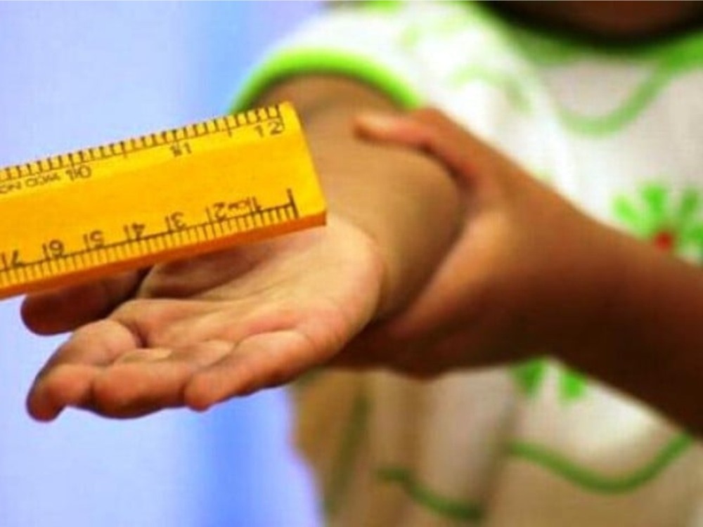 The picture depicts corporal punishment of a child with a ruler. Corporal punishment reduces children’s development chances