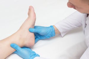 Medical practitioner examining a patient's foot experiencing burning sensation.