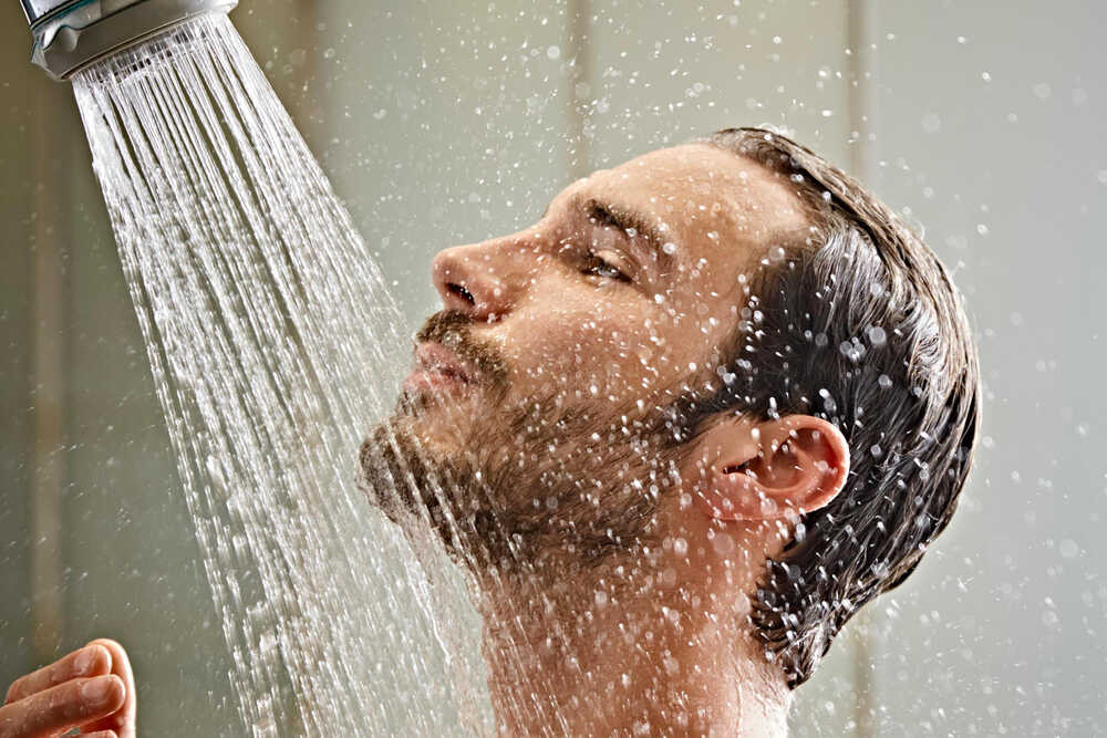A close-up of a modern bathroom shower head releasing water droplets