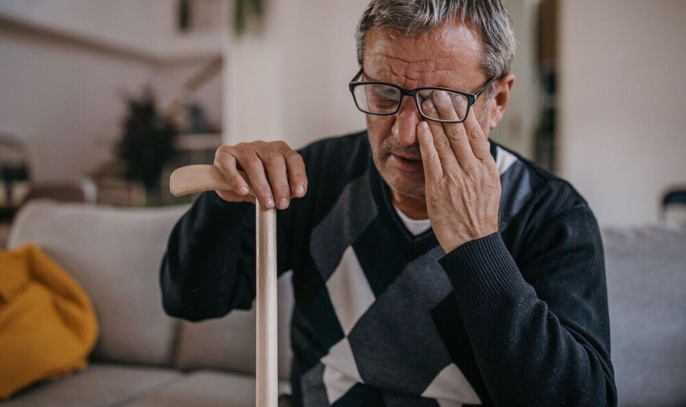 Close-up of a person holding his eye, showing discomfort and eye pain