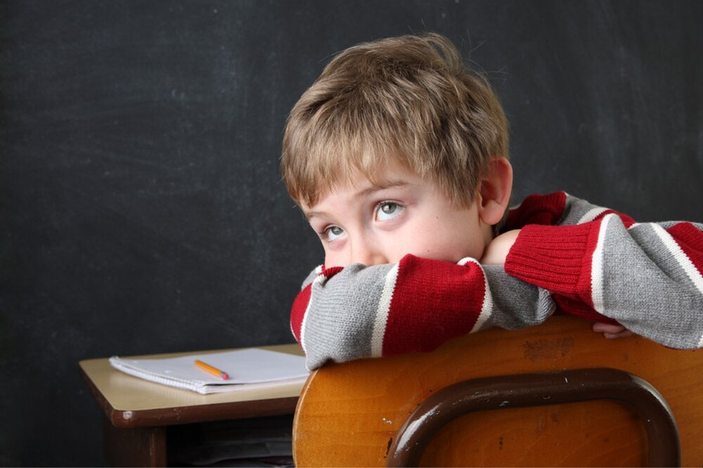 Boy showing ADHD symptoms such as restlessness and difficulty focusing during a classroom activity.