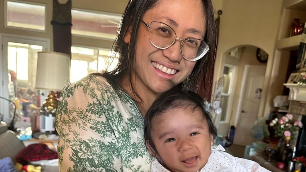 : The mother holding her baby boy after a rare abdominal pregnancy, both healthy and smiling