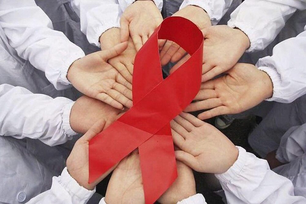 Red ribbon, the symbol of HIV/AIDS on the hands of people