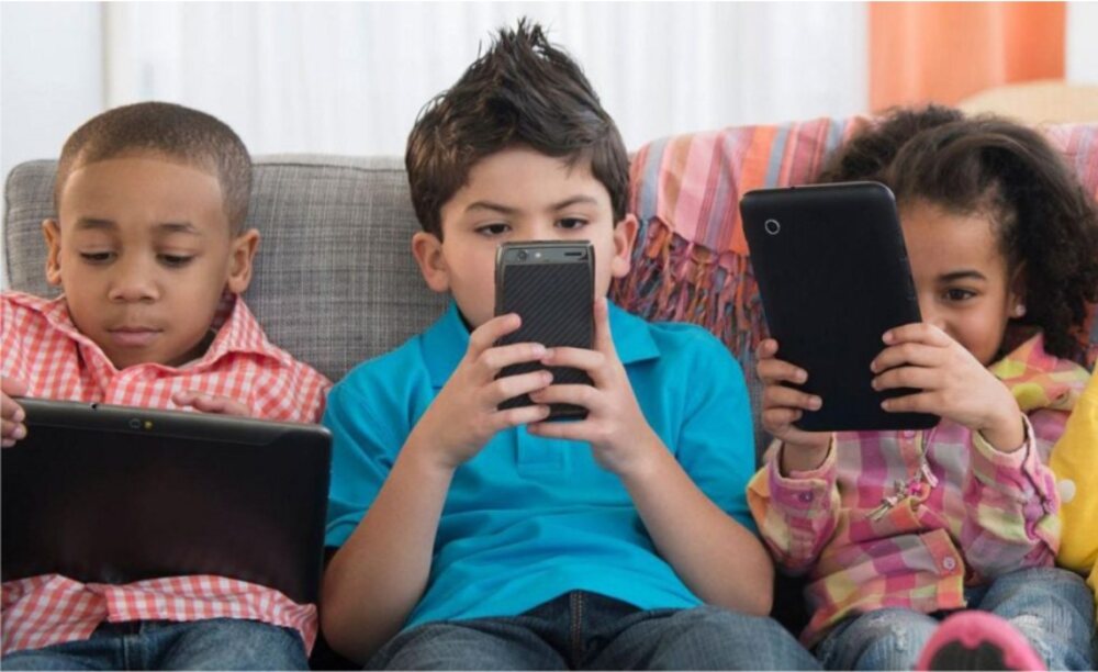 Three children using smartphones indoors, highlighting early screen time and potential health risks for kids
