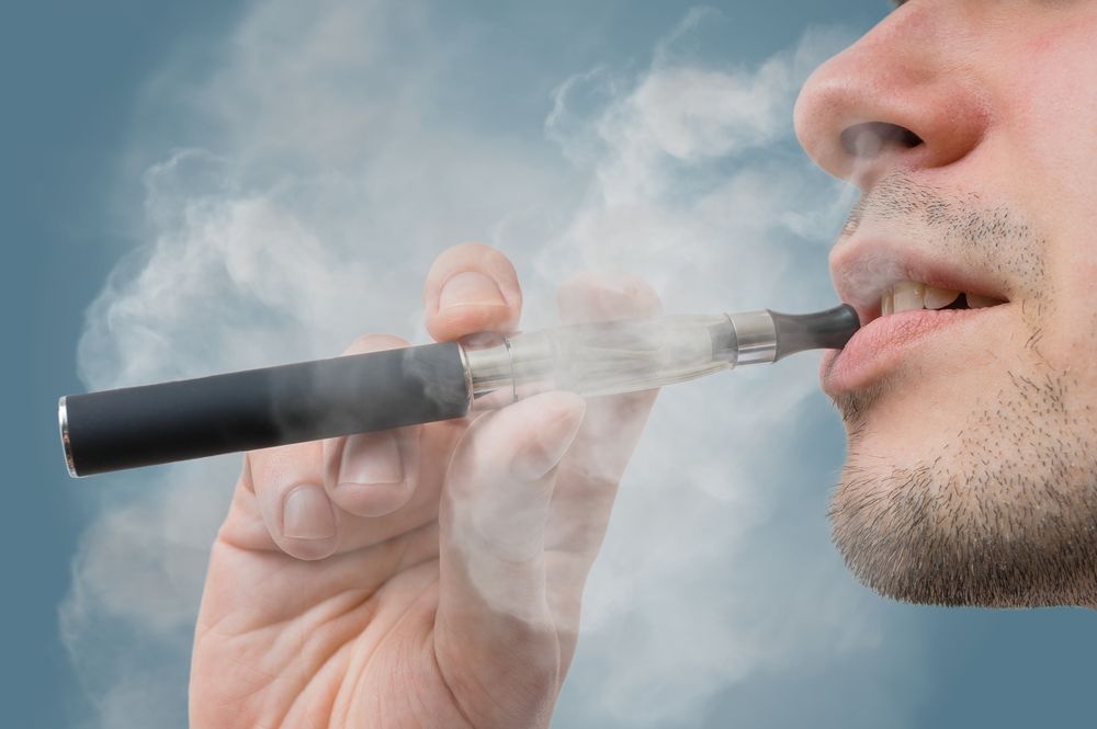 Young man using a vaping device, highlighting rising e-cigarette use among Pakistani youth