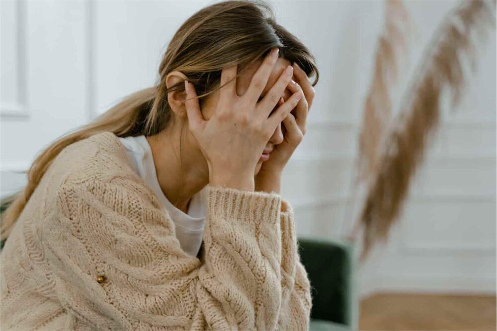 A woman holding her head in stress, illustrating the effects of high cortisol levels on health