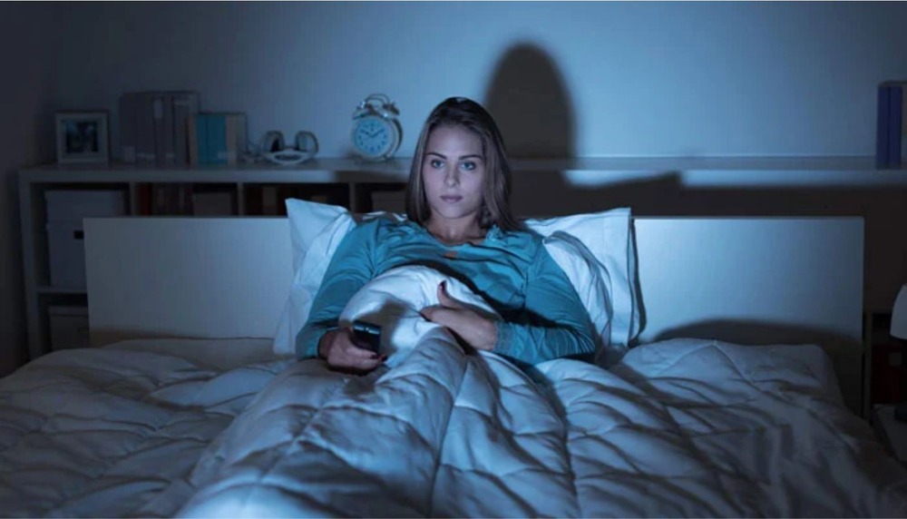 A young woman staying up late at night, symbolizing night owl habits affecting heart health