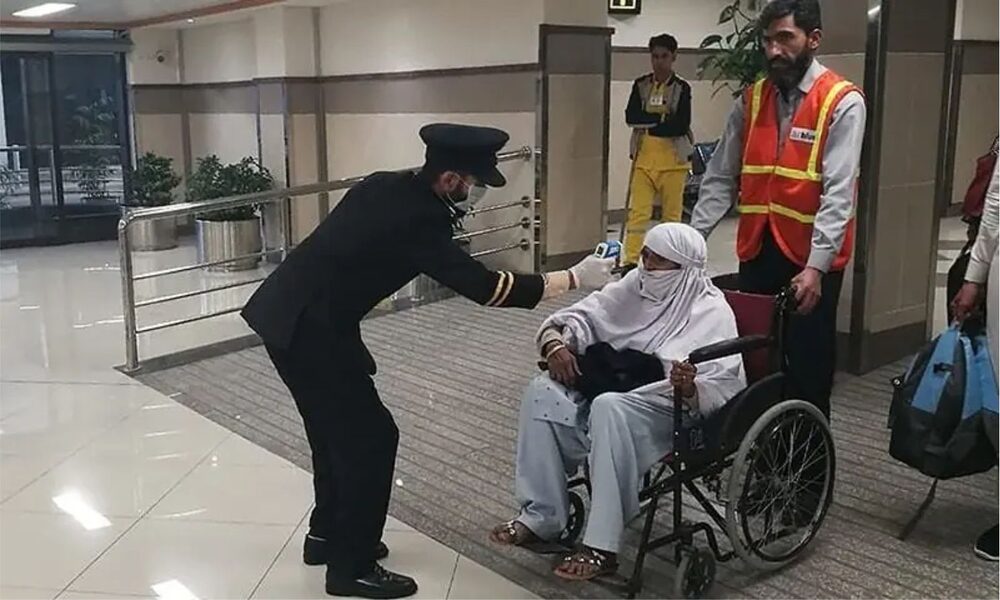 Passenger undergoing health screening for Nipah virus at airport, with medical staff checking temperature and symptoms