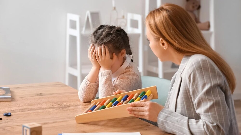 Worried mother sitting beside her young child, showing concern about early signs of autism spectrum disorder