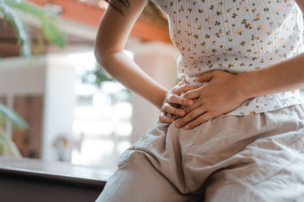 A woman holding her lower abdomen due to pain and discomfort caused by interstitial cystitis (painful bladder syndrome)