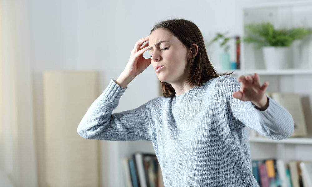 A woman experiencing dizziness while holding her head, illustrating the symptoms of dizziness