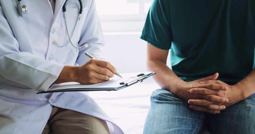 A urologist explaining enlarged prostate (Benign Prostatic Hyperplasia - BPH) to a male patient during a medical consultation