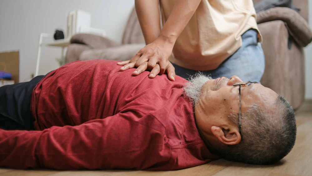 A person performing CPR on a heart patient during a medical emergency.