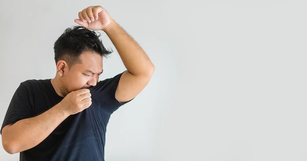 A man experiencing excessive underarm sweating and body odo