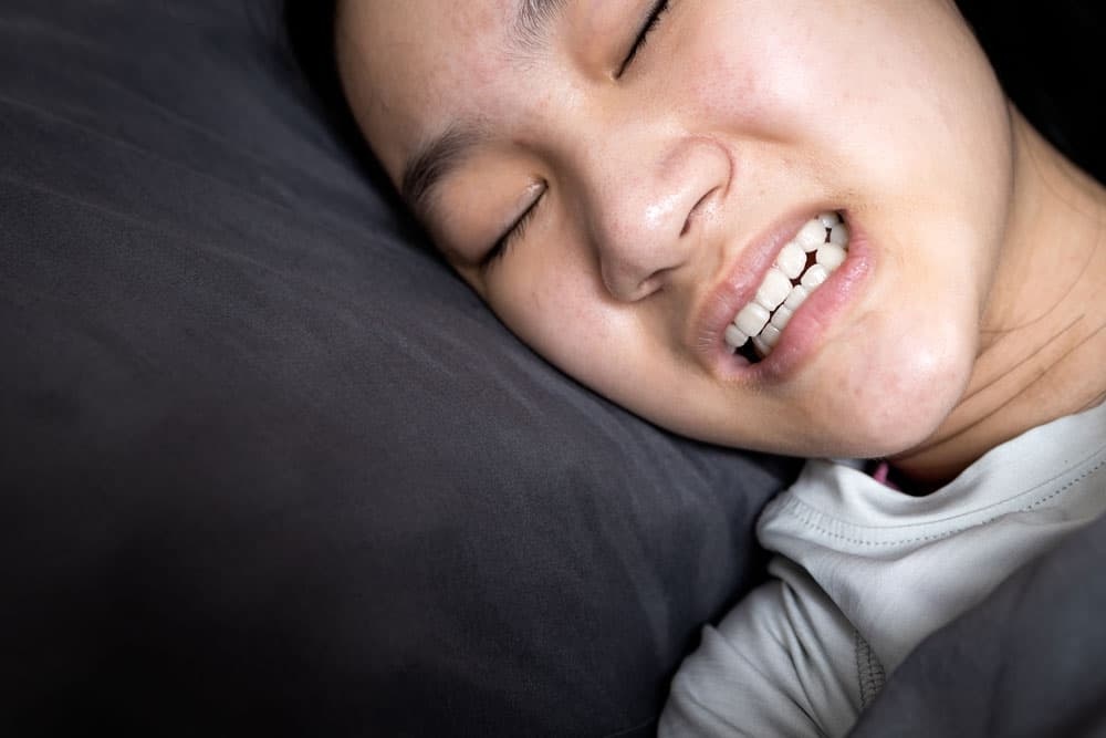 A woman unconsciously grinding her teeth during sleep, illustrating bruxism