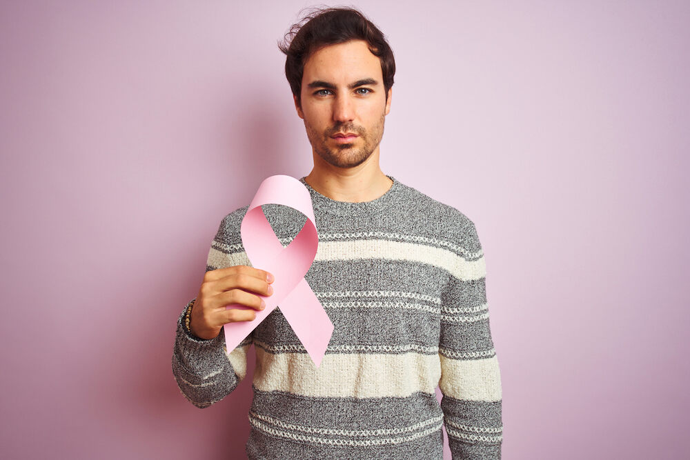 Man holding a pink ribbon to raise awareness about male breast cancer
