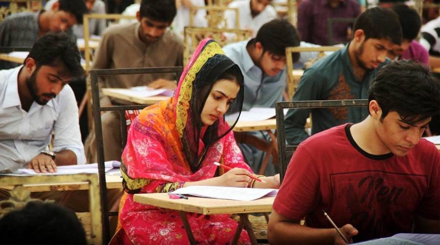 Students writing exam papers in a crowded examination hall, illustrating coverage of the MDCAT 2026 inquiry in Pakistan.