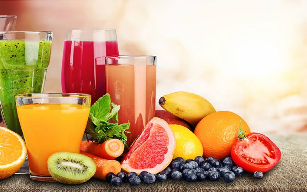 A glass of fruit juice placed beside a bowl of whole fresh fruits, symbolizing the heart-health benefits of choosing whole fruit over juice.